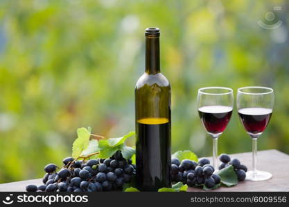 wine bottle and grapes on wooden table outdoor