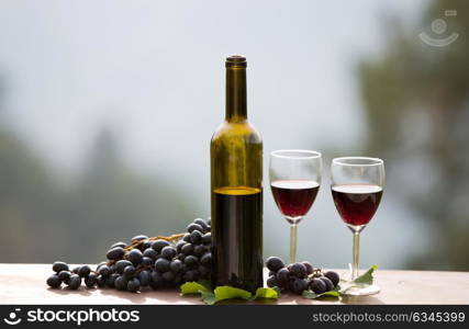 wine bottle and grapes on wooden table outdoor