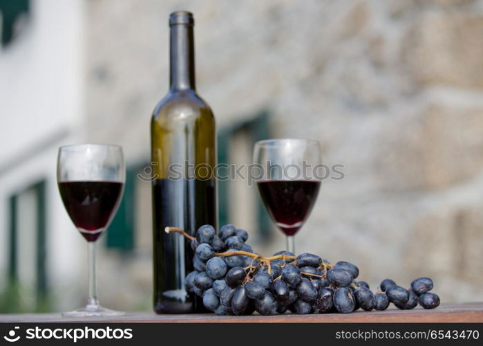 wine bottle and grapes on wooden table outdoor, focus on the grapes. Red wine