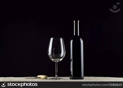 wine bottle, glass and corkscrew on a black background