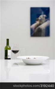 Wine bottle with a glass of red wine and a bowl on a dining table