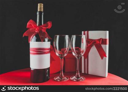 wine bottle with red ribbon two empty glasses