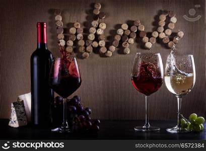 Wine concept Bottle and glasses with red, pink and white splashes of wine on table with word wine written in corks. Glass of red wine