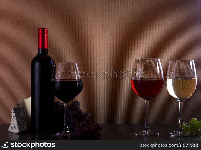 Wine concept - bottle and glasses with red, pink and white wine on table, copy space in background. Glass of red wine