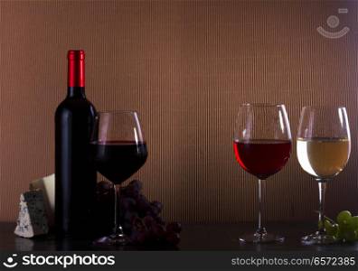 Wine concept - bottle and glasses with red, pink and white wine on table, copy space in background. Glass of red wine