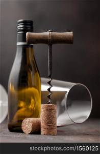 Wine cork with vintage corkscrew on top on wooden background with glass and bottle of white wine