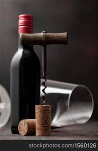 Wine cork with vintage corkscrew on top on wooden background with glass and bottle of red wine