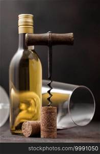 Wine cork with vintage corkscrew on top on wooden background with glass and bottle of white wine
