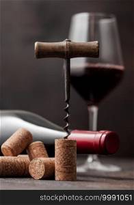 Wine cork with vintage corkscrew on top on wooden table background with glass of red wine