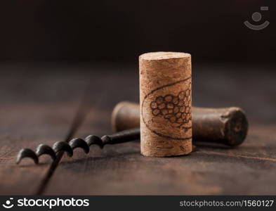 Wine cork with vintage corkscrew on wooden board background.