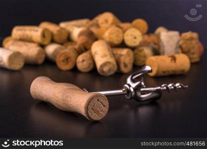 Wine corks and corkscrew on black wooden table