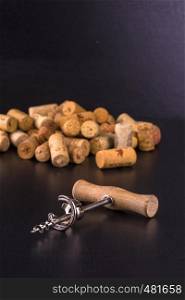 Wine corks and corkscrew on black wooden table