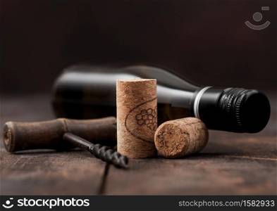 Wine corks with vintage corkscrew and bottle of white wine on wooden table background.