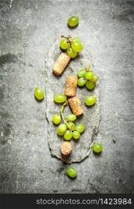 Wine corks with white grapes. On the stone table.. Wine corks with white grapes.