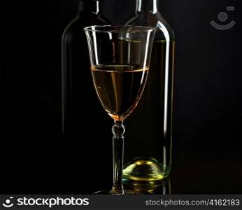 wine glass and bottles on black background