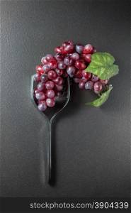 Wine glass made of forks and grape on black background