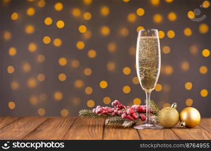 Wine glass with bubbly ch&agne and fir branch with decor on background of blurry sparkling lights. Happy New Year holiday greeting card, banner, header with copy space