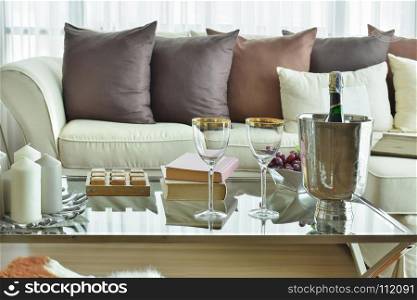 Wine glasses and wine bottle on table with beige sofa with dark brown pillows in modern classic living room