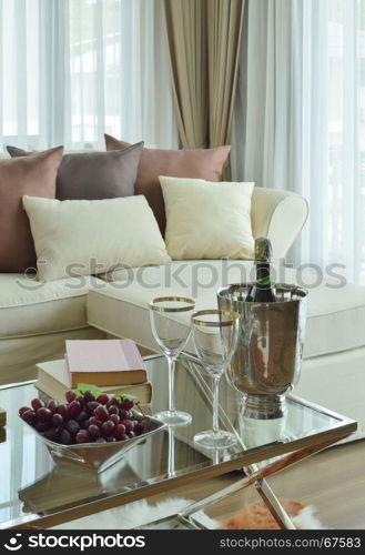 Wine glasses and wine bottle on table with beige sofa with dark brown pillows in modern classic living room