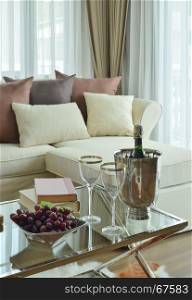 Wine glasses and wine bottle on table with beige sofa with dark brown pillows in modern classic living room
