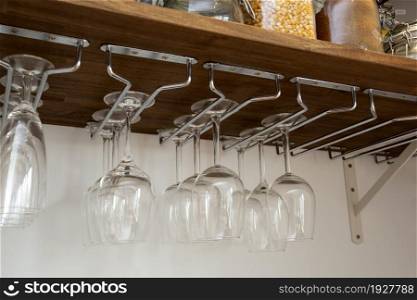 Wine glasses hanging in holder. organized inside cupboard. home interior storage close up. Wine glasses hanging in holder. organized inside cupboard. home interior storage