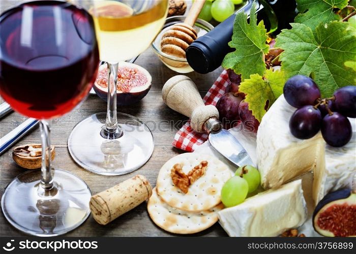 Wine, grape and cheese on wooden background
