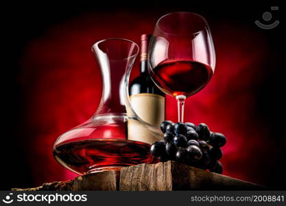 Wine in a decanter and glass on a wooden table. Decanter wine and grapes