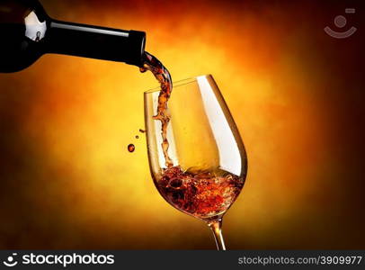 Wine pouring in wineglass on an orange background