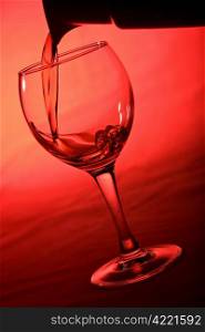 wine pouring into glass over red background