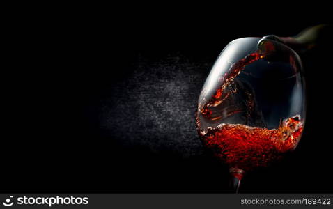 Wine pouring into wineglass on textured black background