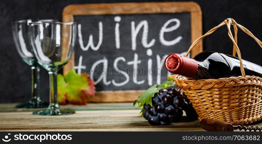 Wine tasting concept. Wine in basket with grapes, leaves and corks on dark background, copyspace