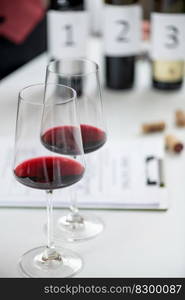 Wine tasting form with glasses and bottles of red wine in background