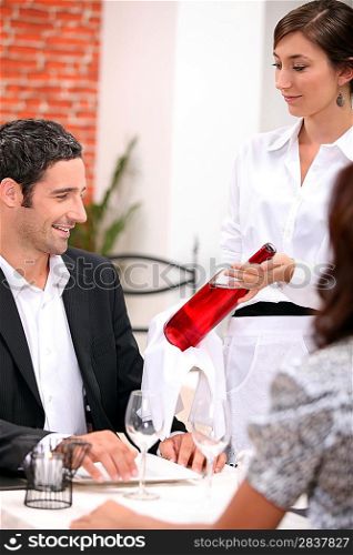 wine waitress showing a wine bottle to a customer