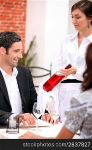 wine waitress showing a wine bottle to a customer