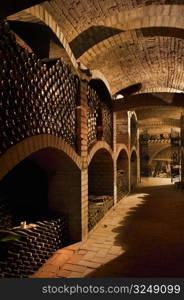 Winebottles stacked in the old cellar of the winery.