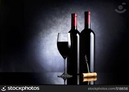 Wineglass and two bottles of wine on a black background