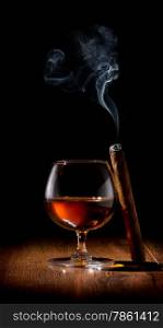 Wineglass of scotch and cigar on wooden table