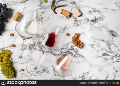 Wineglasses with red, pink and white wine on white calacatta background with copy space. Wineglasses with grapes