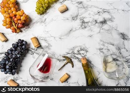 Wineglasses with red wine, fresh grapes and corks on white calacatta background with copy space. Wineglasses with grapes
