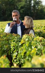 Winegrowers in the vineyard with a glass of wine