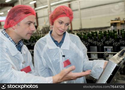 winemaker and assistant examining sample of wine