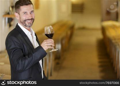winemaker tasting red wine in cellar
