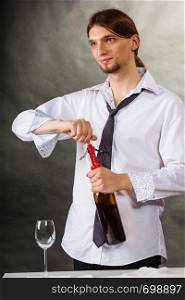 Winery serving tasting alcohol liquor concept. Waiter opens wine bottle. Young male sommelier pulls out cork. . Waiter opens wine bottle.