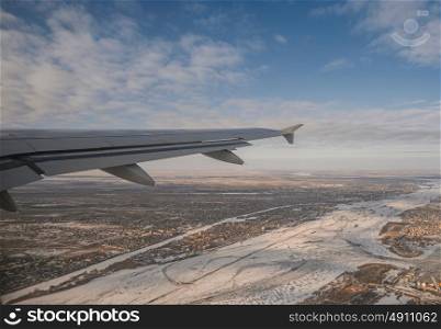 Wing of aircraft over frozen river copyspace on the sky