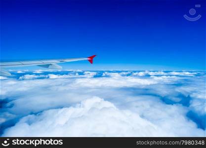 Wing of airplane flying in sky above clouds. Airplane flying above clouds
