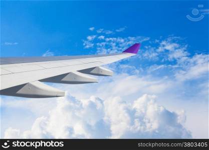 Wing of an airplane flying above the clouds. people looks at the sky from the window of the plane, using air transport to travel