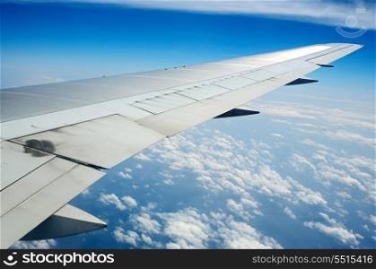 Wing of an airplane with a nice aerial view of the sky with clouds