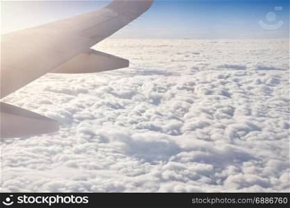 Wing of an airplane with sunlight above the cloud