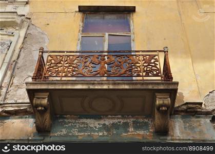 Winged female figure rusty floral pattern and swans on balcony balustrade of abandoned neoclassical house. Athens Greece.