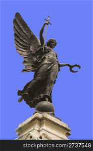 "Winged statue of Victory in Colchester War Memorial. In her right hand she is holding a sword, point downwards so that it represents "The Cross of Sacrifice" and "The Sword of Devotion," and in her left a wreath of laurel. "